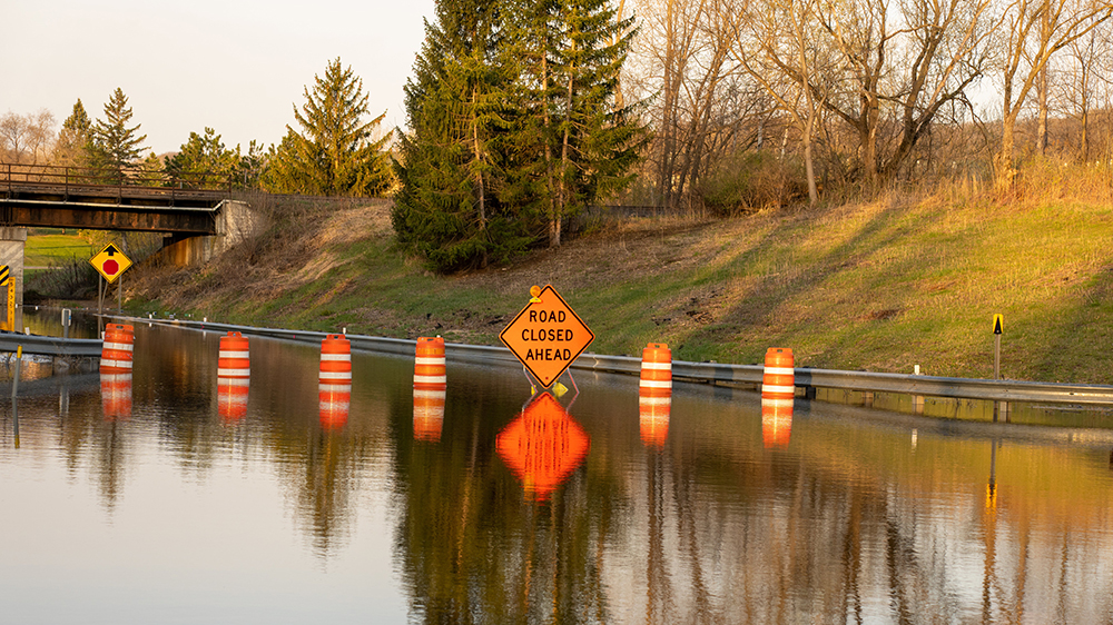 Flooded freeway with 'road closed ahead' sign